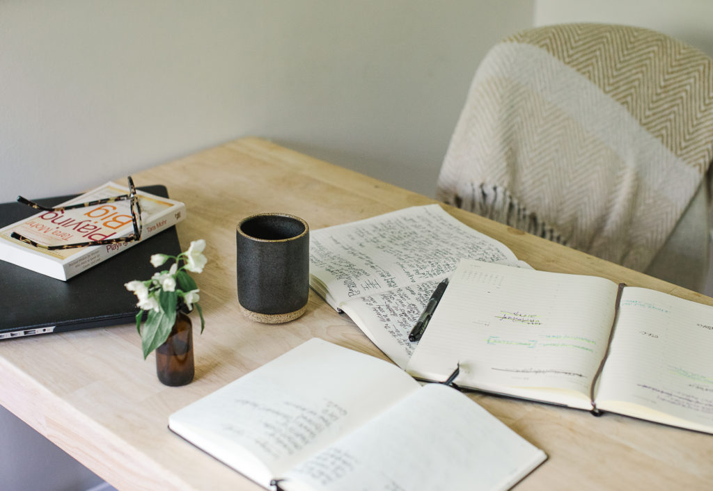 Calendar, jounrals, and the book Playing Big by Tara Mohr on a desk. 